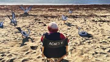 Agnès Varda sitting in chair on the beach