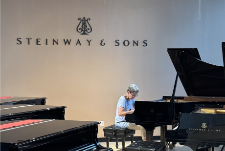 A pianist sits at a piano in the Steinway & Sons Factory showroom